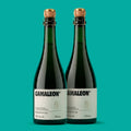 Duas garrafas de Camaleon, fermentado de cana 750 ml, lado a lado em fundo verde