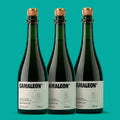 Três garrafas de Camaleon, fermentado de cana 750 ml, lado a lado em fundo verde